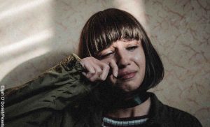 Foto de una mujer llorando contra una pared que revela las mejores películas de drama