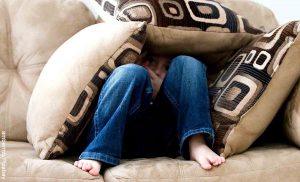 Foto de un niño debajo de almohadas que revela las mejores películas de miedo