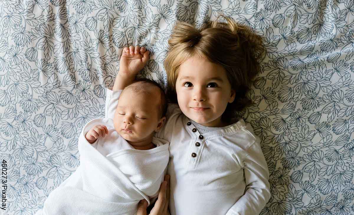 Foto de una bebé junto con su hermana acostada en la cama que muestra los nombres de niñas con significado