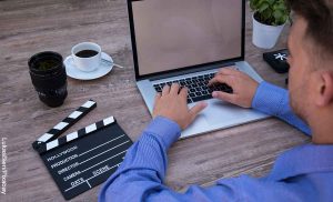Foto de un hombre sentado frente a su computador que revela las páginas para ver películas gratis