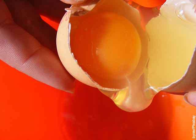 Foto de la yema y la clara de un huevo saliendo de una cáscara que muestra lo que es soñar con huevos rotos
