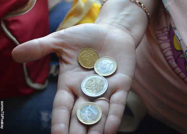 Foto de una persona con 4 monedas en su palma de la mano