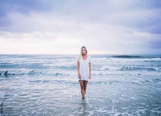 Foto de una mujer en la orilla de la playa que muestran lo que es soñar con olas grandes