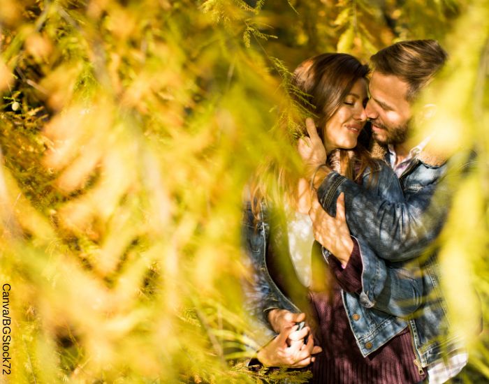 Foto de una pareja abrazada detrás de unos árboles