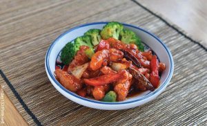 Foto de pollo y vegetales en un plato que revela cómo hacer salsa agridulce