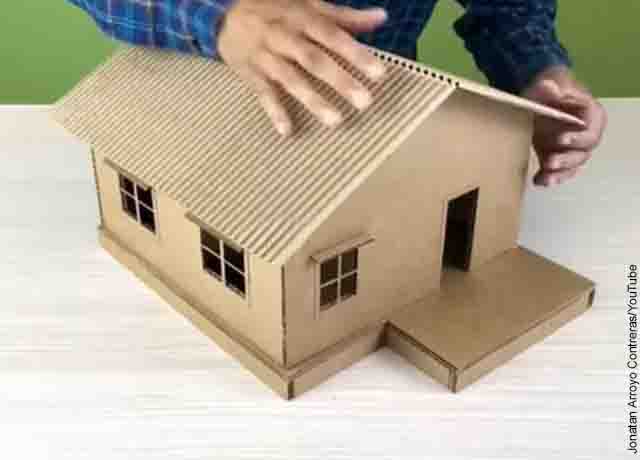 Foto de una persona pegando un techo de cartón a una casa