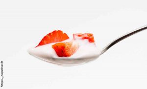 Foto de una cucharada de yogurt con fresa que revela cómo hacer yogurt griego