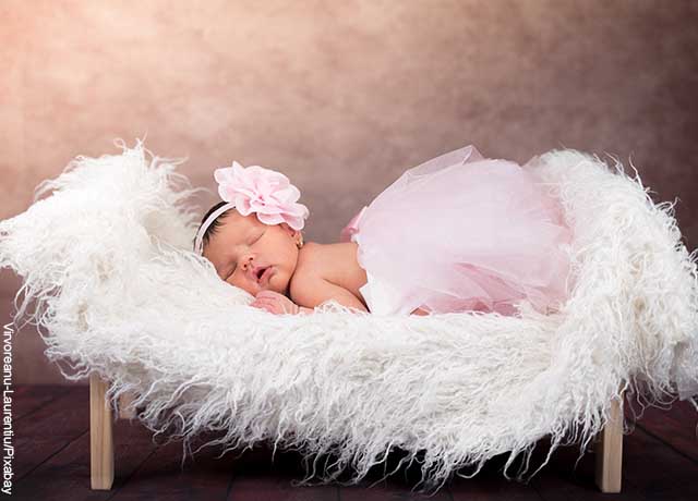 Foto de una recién nacida durmiendo sobre una cama de plumas
