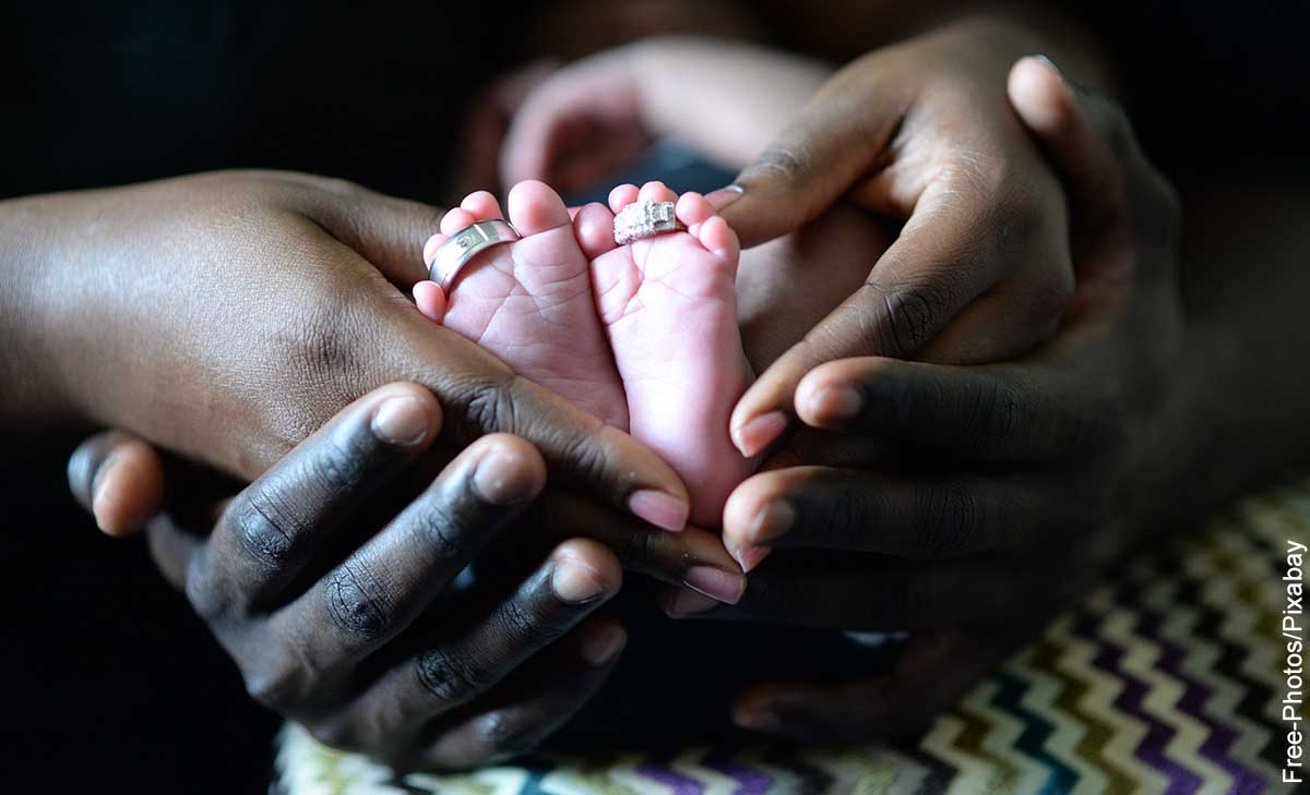 Foto de una persona sosteniendo los pies de su hijo que muestra qué significa soñar con tener un bebé