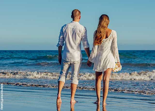 Foto de una pareja tomada de la mano caminando por la playa que muestra qué significa soñar con tu ex novio que regresan
