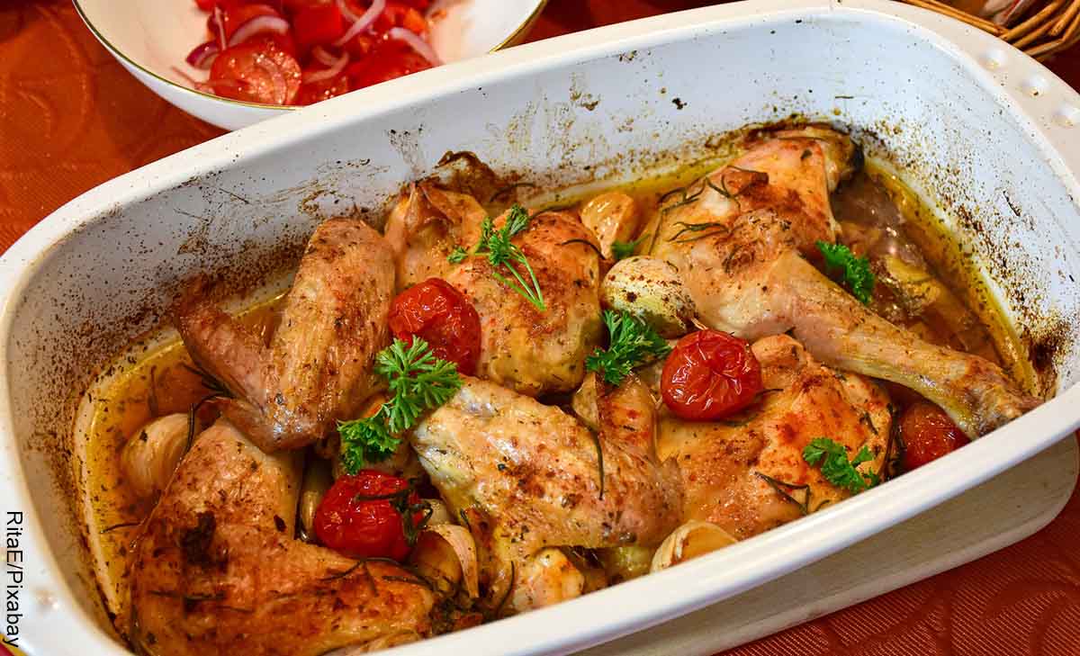 Foto de un recipiente con presas de pollo y tomates que revela las recetas de pollo fáciles y económicas