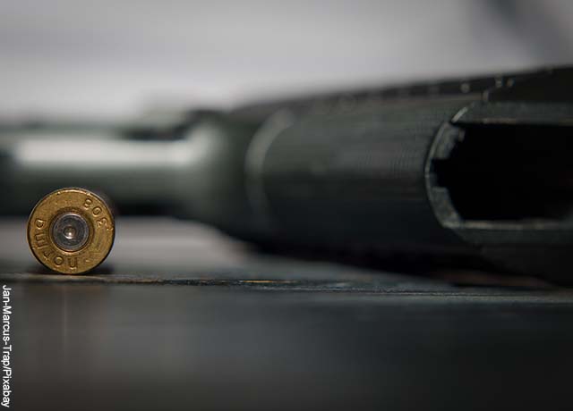 Foto de una pistola y una bala sobre una mesa que revela lo que es soñar con armas de fuego
