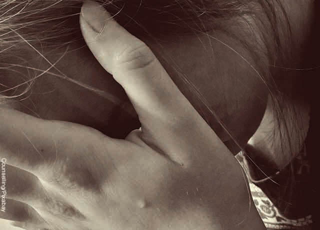 Foto de una joven llorando con una mano en su cara