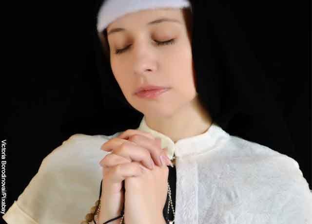 Foto de una monja rezando con una camándula