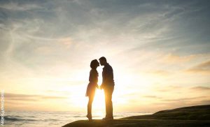Foto de una pareja besándose en una playa que muestra las canciones románticas para dedicar
