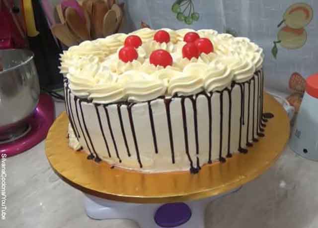 Foto de una torta con cobertura de chocolate y cerezas