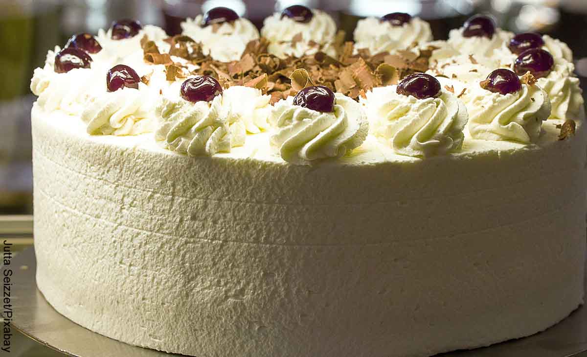 Foto de una torta con cobertura blanca que tevela cómo hacer crema para decorar torta