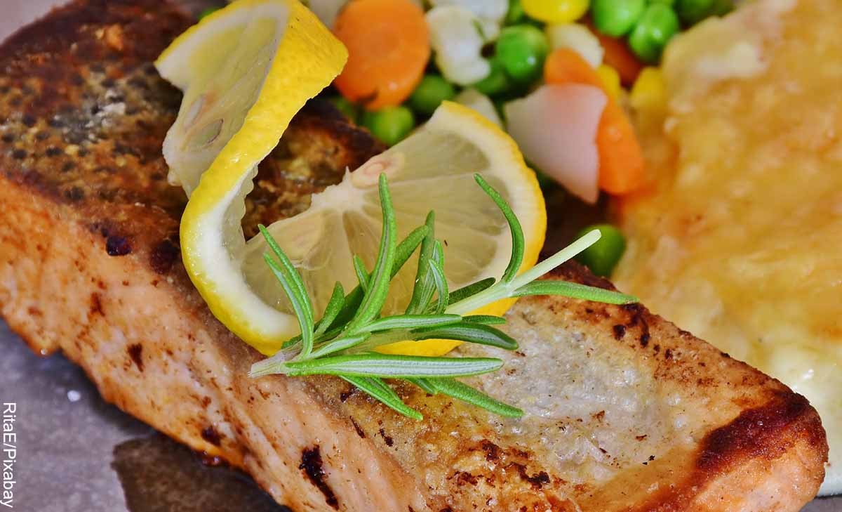 Foto de un trozo de salmón con limón y vegetales