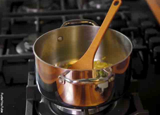 Foto de cebolla fritando en una olla que revela cómo hacer salsa de tomate