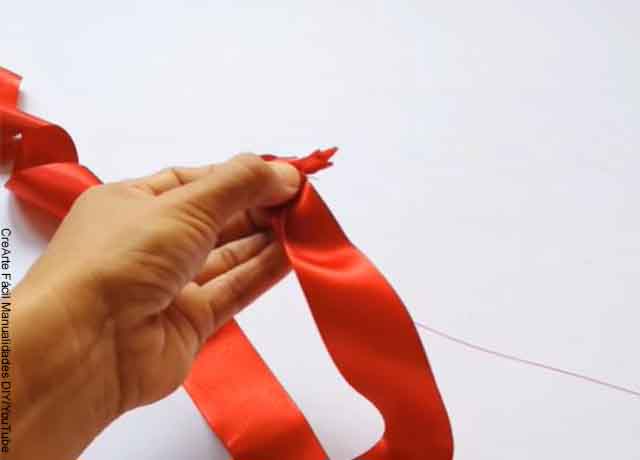 Foto de una conta roja con hilo y aguja