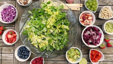 Foto de lechuga en un bol y verduras y frutas sobre la mesa que muestran las recetas de ensaladas