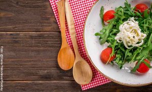 Foto de un plato con tomates, lechuga y queso sobre una mesa de madera que revela las recetas de ensaladas saludables