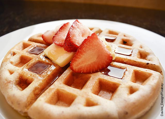Foto de un waffle con miel y fresas