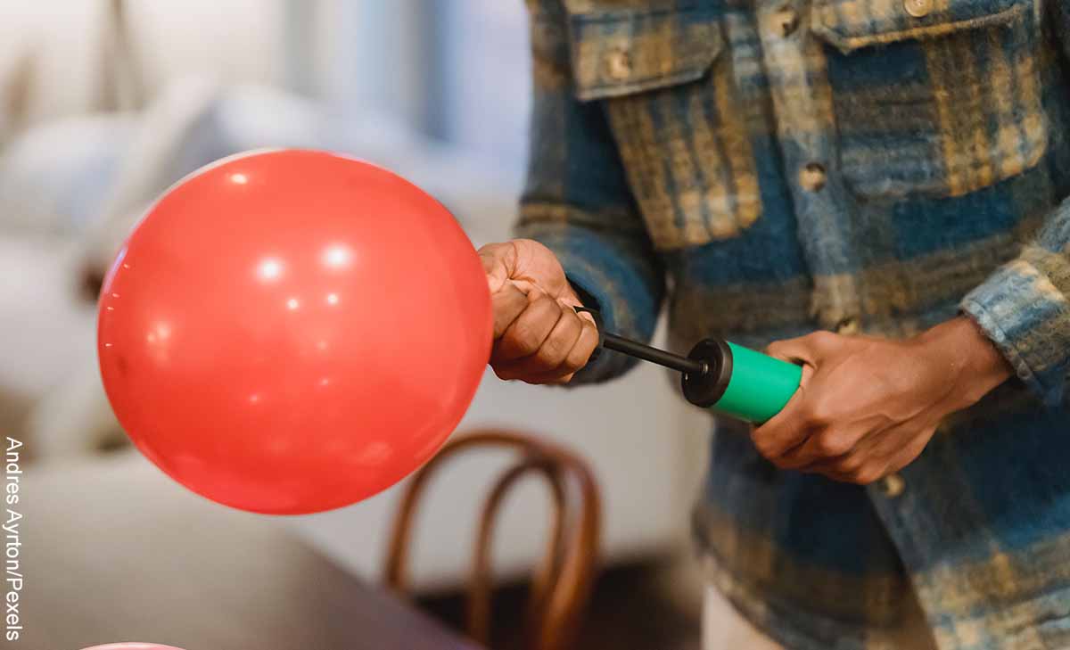 Foto de una persona inflando un globo que revela cómo hacer decoración con globos