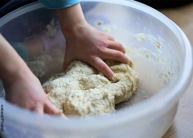 Foto de unas manos amasando harina en un bol