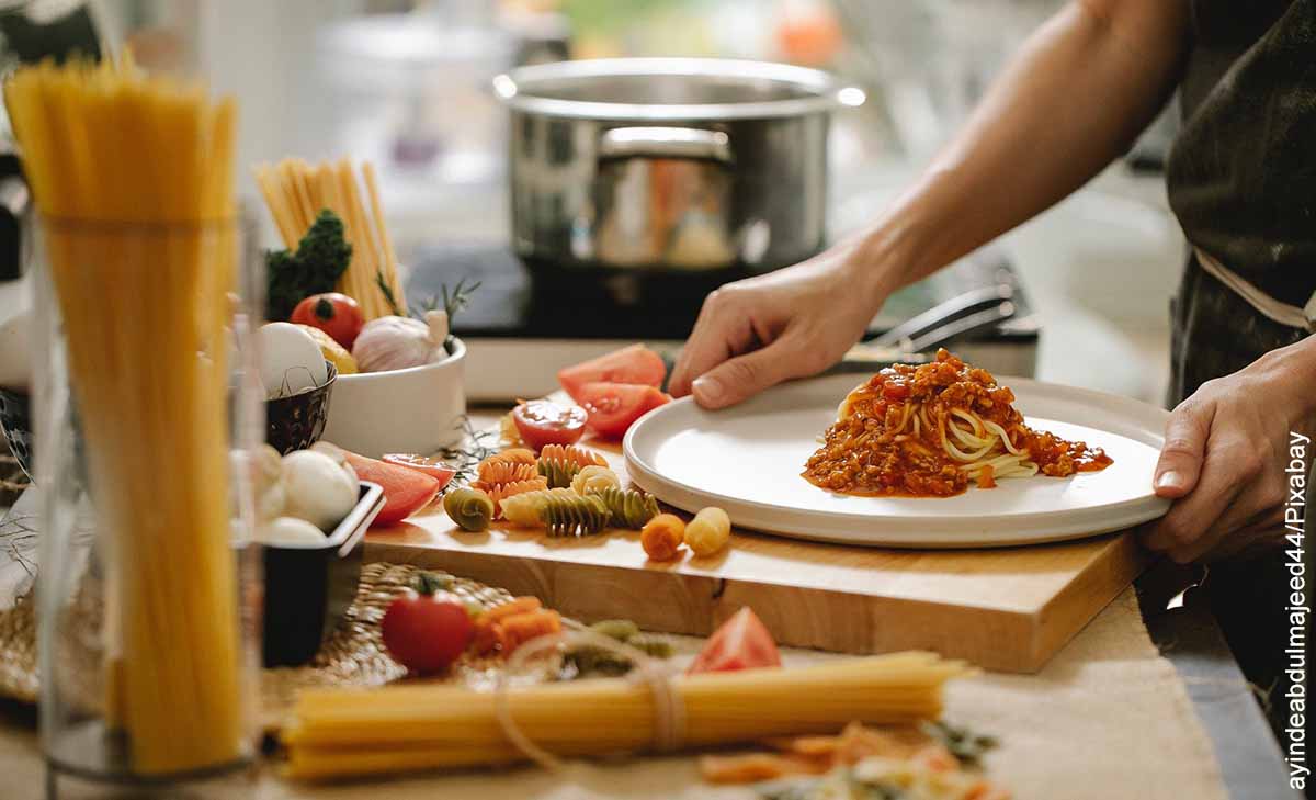 Foto de una persona sirviendo pasta en un plato blanca que ilustra cómo hacer espaguetis caseros