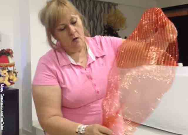 Foto de una mujer sosteniendo una malla que indica cómo hacer moños de navidad