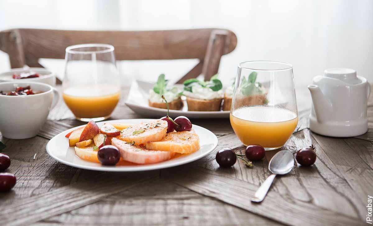 Foto de un desayuno en la mesa con jugo y frutas que revela cómo hacer un desayuno sorpresa para hombre