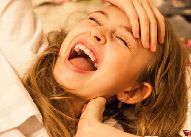 Foto de una niña riendo con los ojos cerrados