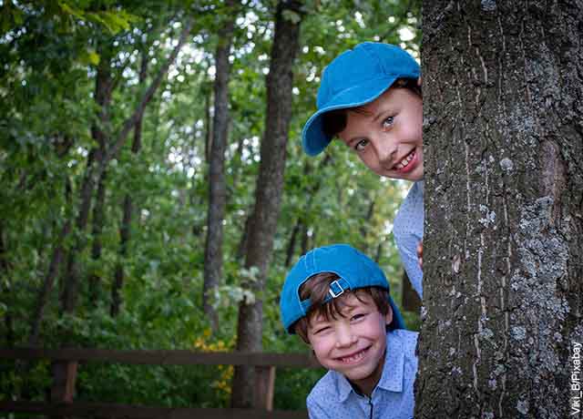 Foto de dos niños escondidos tras un árbol