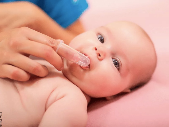 Foto de bebé con dedal para lavar la boca