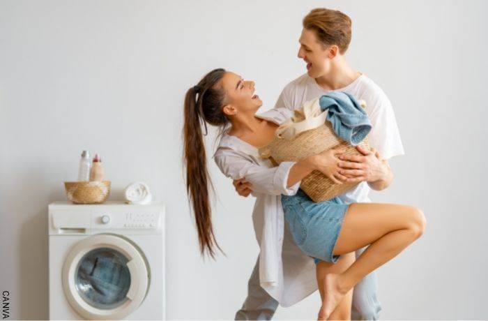 Foto de una pareja bailando mientras lavan la ropa en lavadora