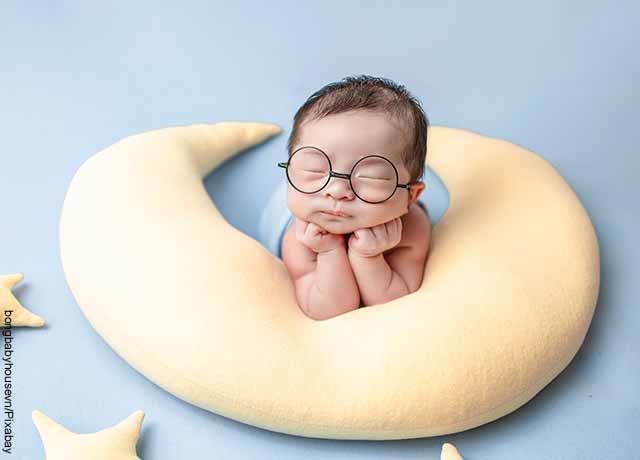 Foto de un bebé sobre una almohada en forma de luna