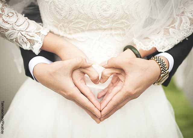 Foto de una pareja de casados formando un corazón con las manos