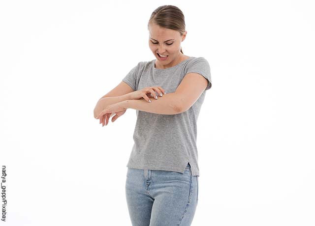 Foto de una mujer rascándose el brazo que revela soñar con zancudos