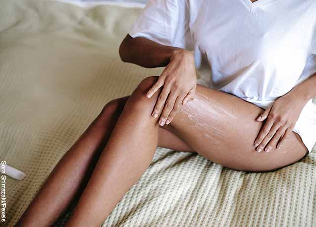 Foto de una mujer aplicando crema en su pierna izquierda