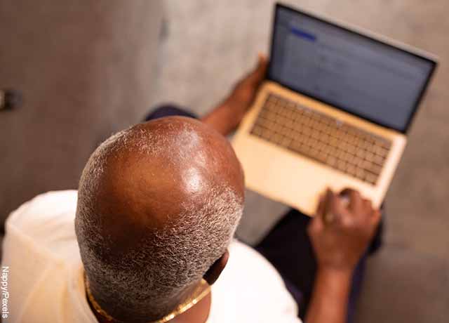 Foto de un hombre calvo mirando su computador que muestra los masajes para el cabello