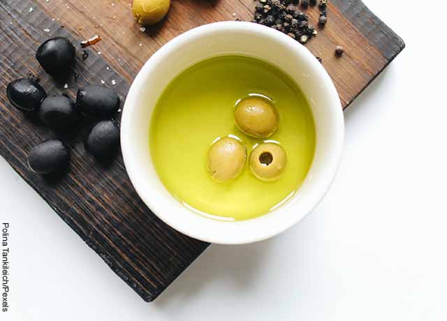 Foto de aceite de oliva con aceitunas en un bol