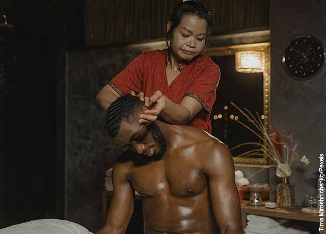 Foto de una mujer haciéndole un masaje de cuello a un hombre