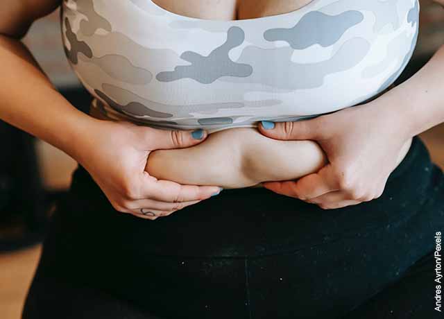 Foto de una mujer tomando su estómago que muestra los masajes reductores de abdomen
