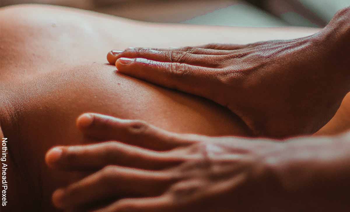 Foto de unas manos sobre la espalda de una persona que revela cómo hacer los masajes terapéuticos