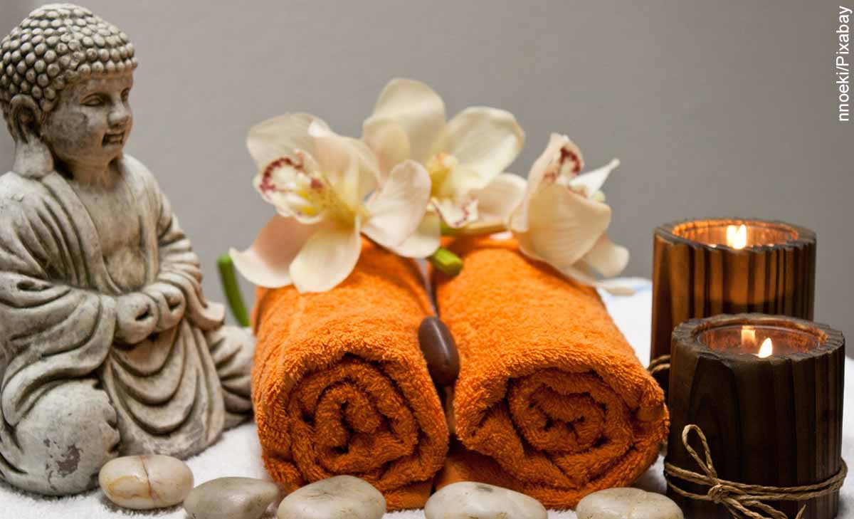Foto de un Buda, unas toallas y unas velas que muestran los masajes milenarios