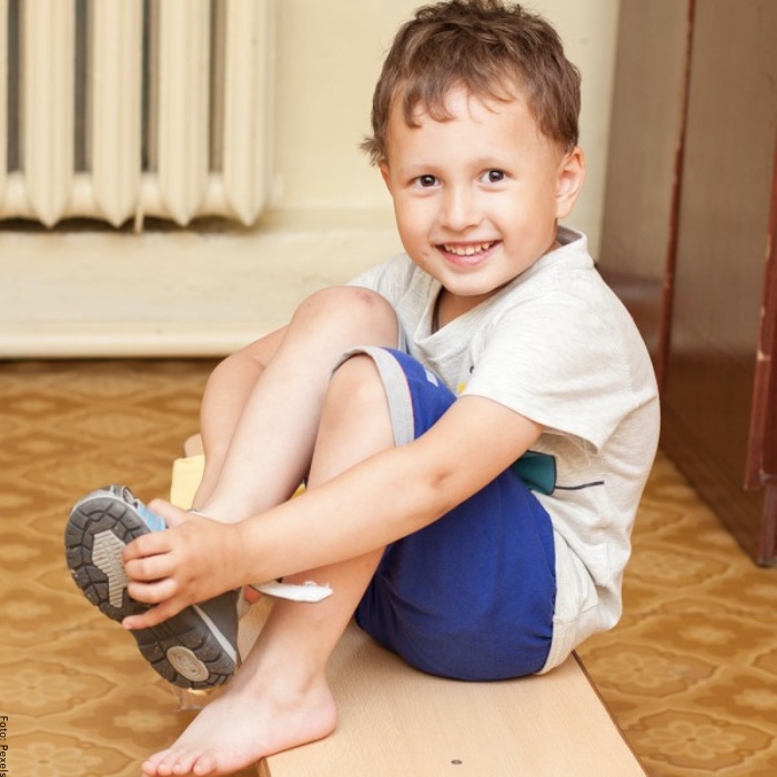 Foto de un niño poniéndose los zapatos