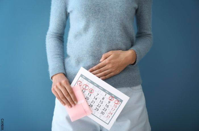 Foto de mujer con un calendario en la mano y la otra sobre el vientre