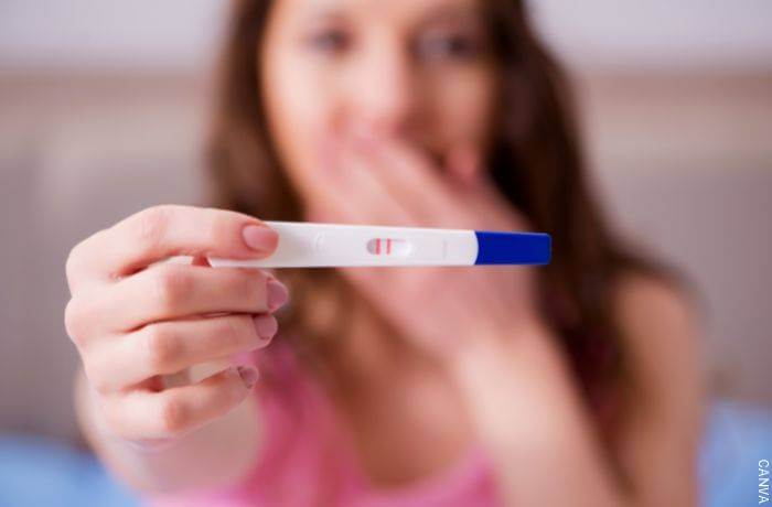 Foto de mujer mostrando una prueba de embarazo positiva