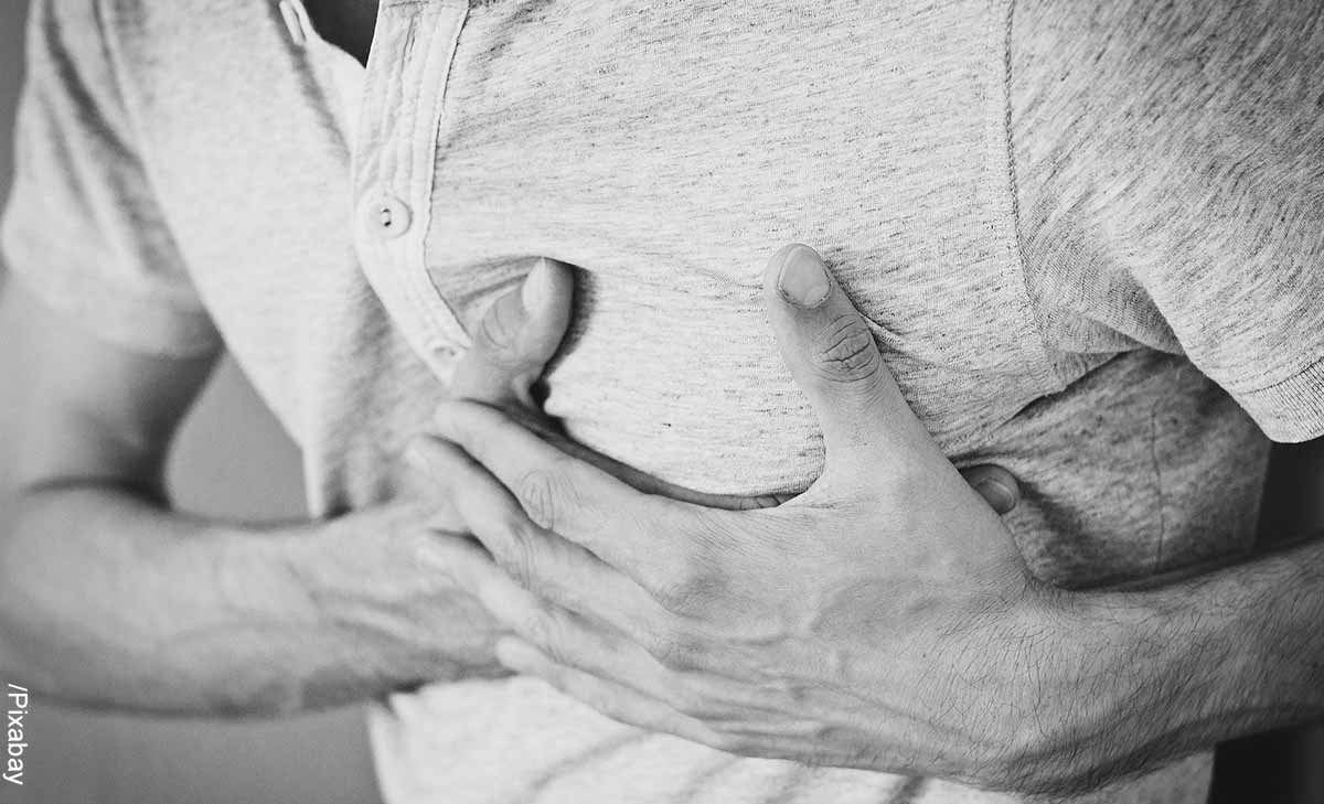 Foto de un hombre que se toma el pecho que muestra el masaje cardíaco